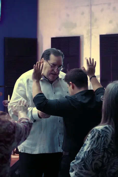 Pastor Samuel blessing a young man as the church prays