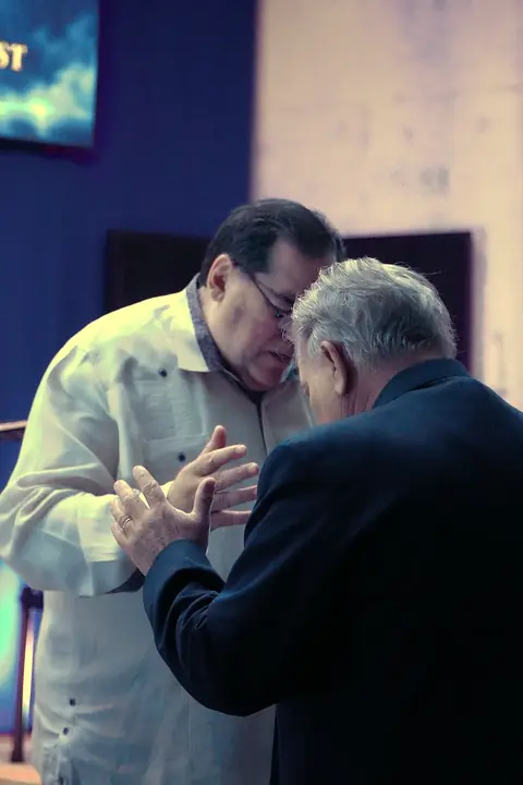 Pastor Samuel praying with a brother in the church
